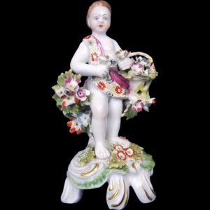 An English Bow Porcelain Figure Of A Putti Holding Basket With Flowers Standing